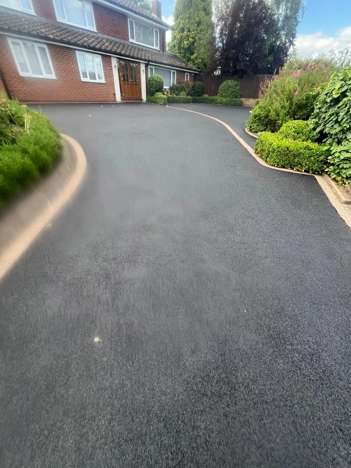 Curved tarmac driveway fully restored to jet black with mature garden borders