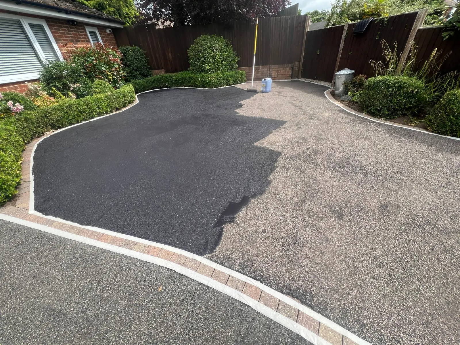 Curved tarmac driveway half treated showing the contrast between faded and restored surface